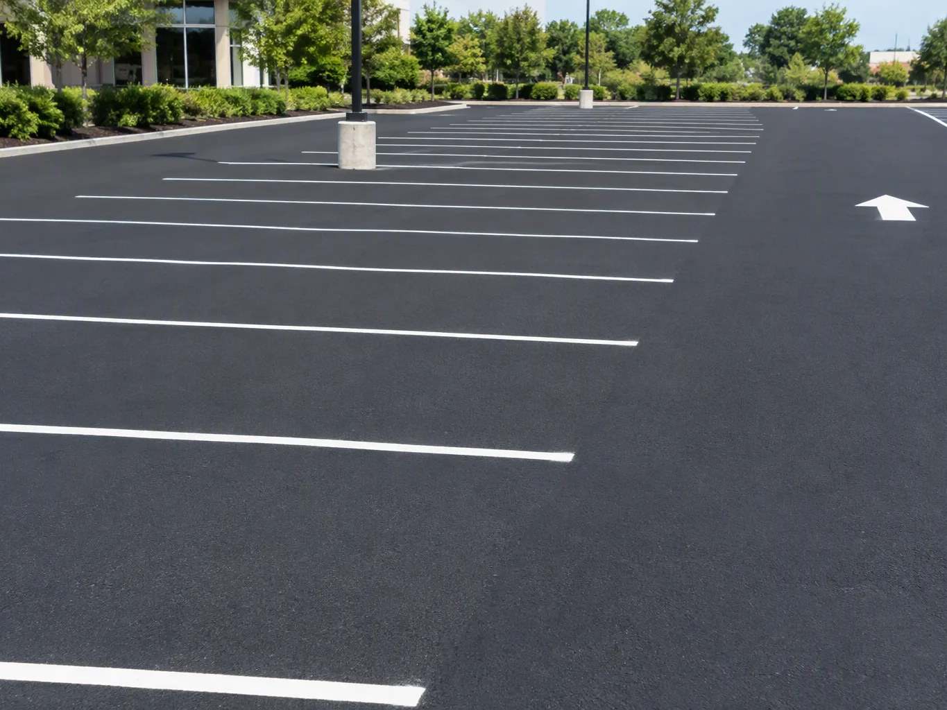 During the application stage of a line striping project, a striping contractor guides a walk-behind line striping machine along a freshly marked parking stall while keeping attention on the paint path